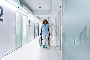 Doctor assisting a patient in a wheelchair at a walk-in clinic entrance.