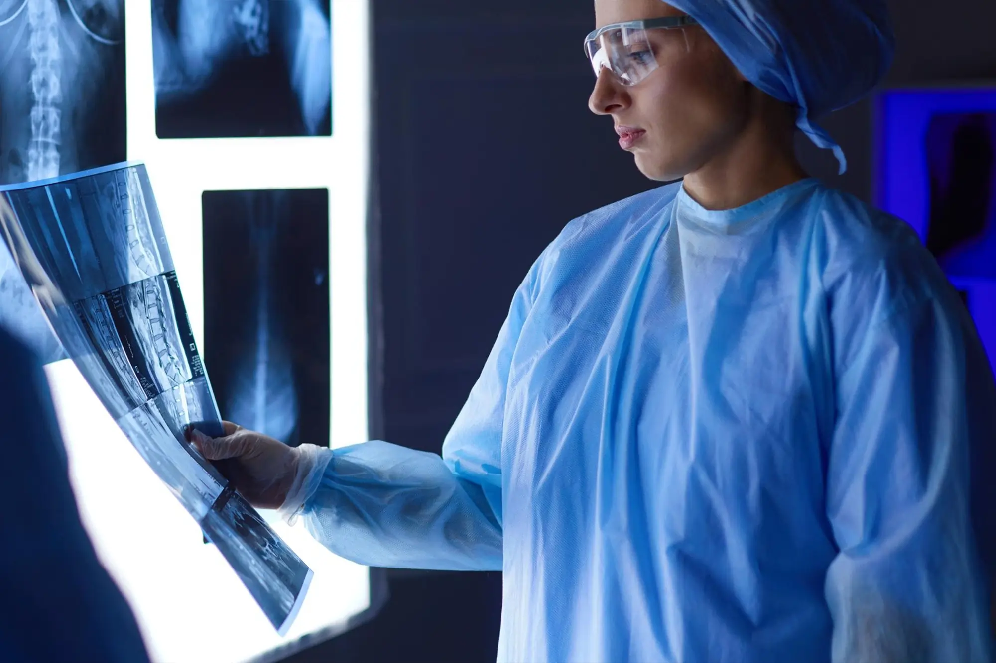 Radiographer analyzing an X-ray film in a clinical lab setting, representing diagnostic testing and imaging services.