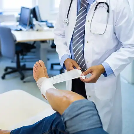 Medical professional treating a leg injury with proper wound care and bandaging.