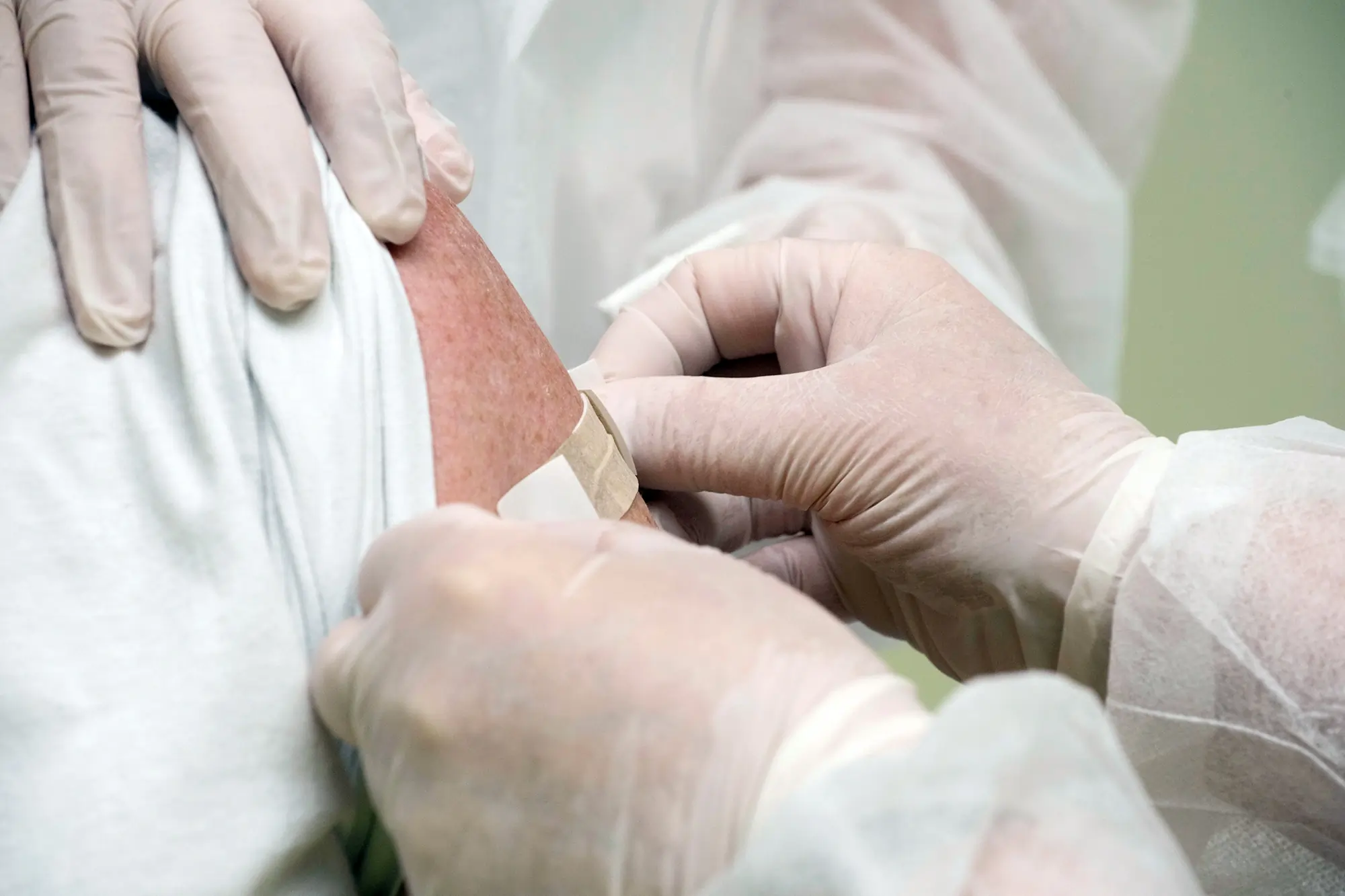 A doctor carefully applying bandages to a patient's wound during treatment.