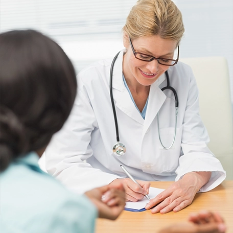 Female doctor consulting with her patient while writing notes on a medical chart during an appointment.