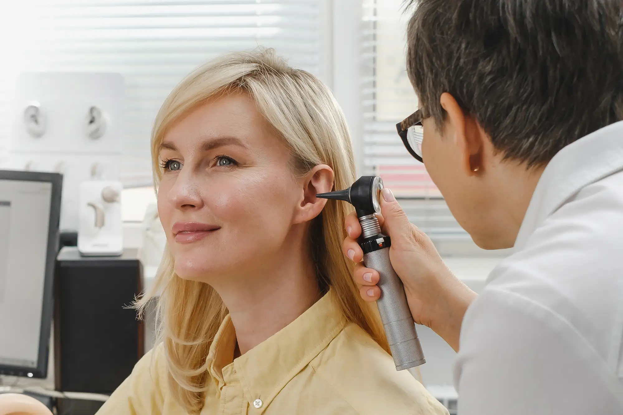 Doctor examining a woman’s ear to diagnose a middle ear infection.