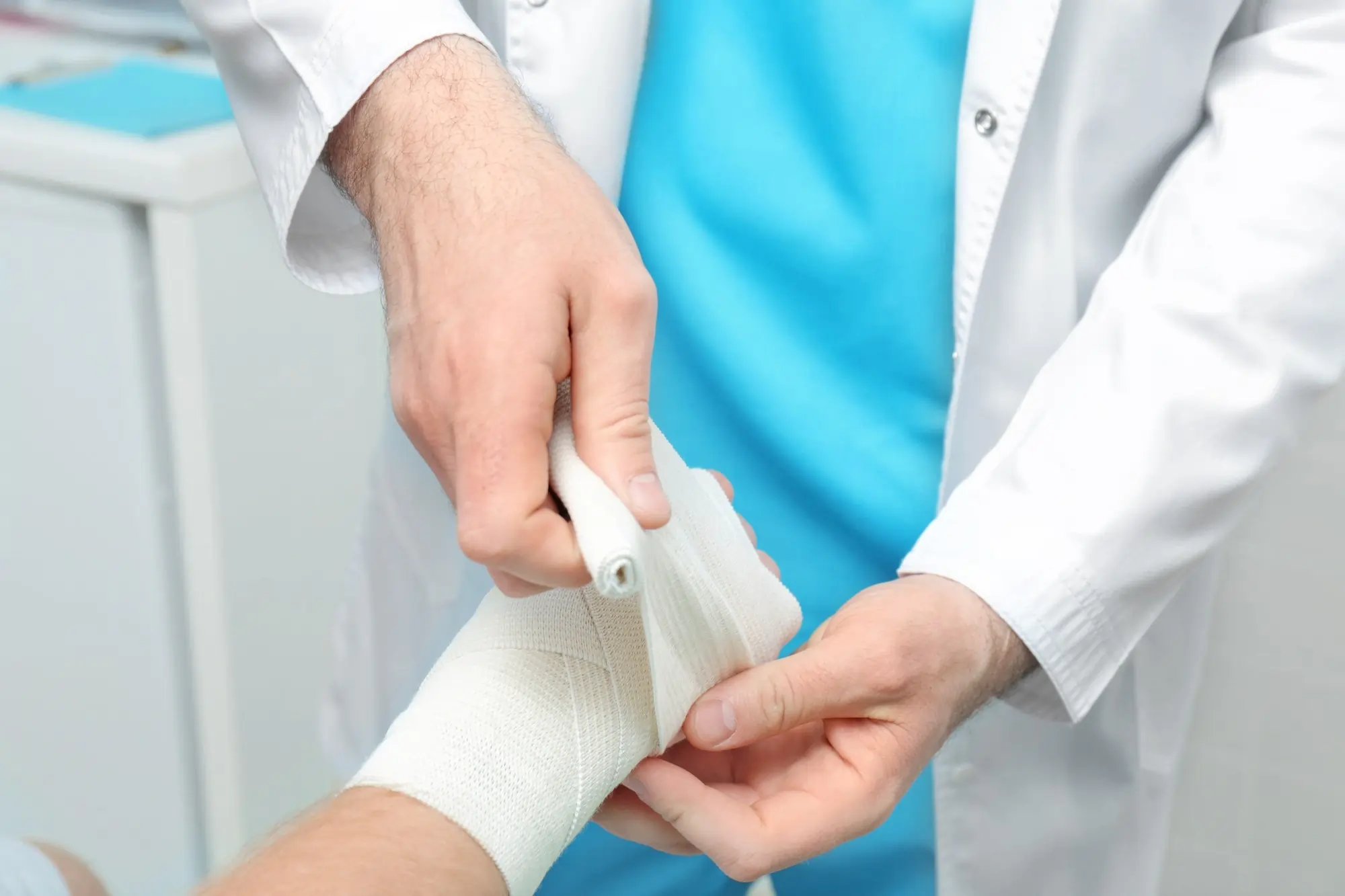 Doctor gently dressing a patient's broken arm after cleaning the wound in a clinical setting.