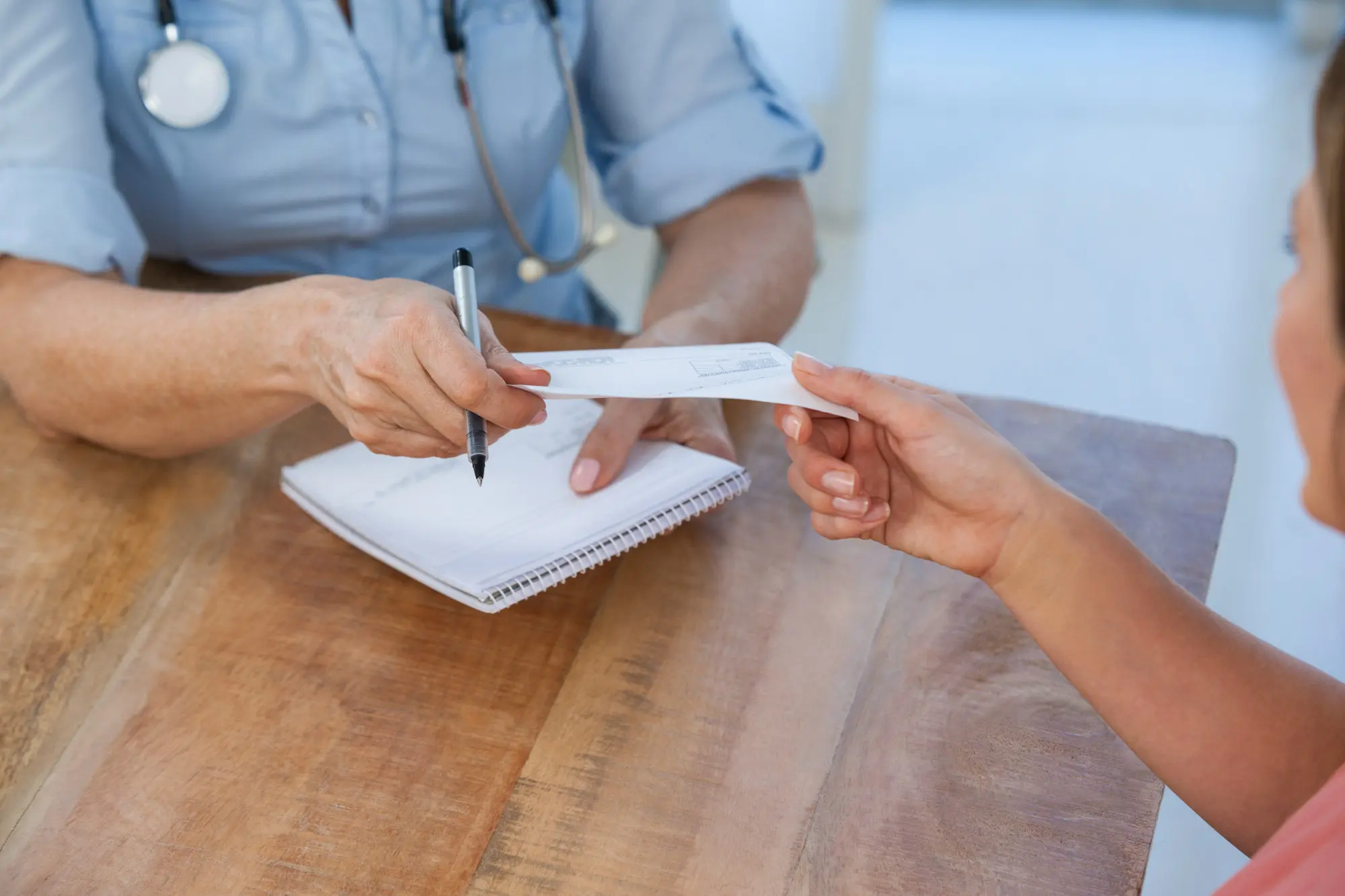 Doctor handing a prescription to a patient as part of ongoing medical care.