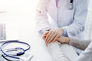 Doctor holding patient's hand to provide comfort and support during urgent care visit.