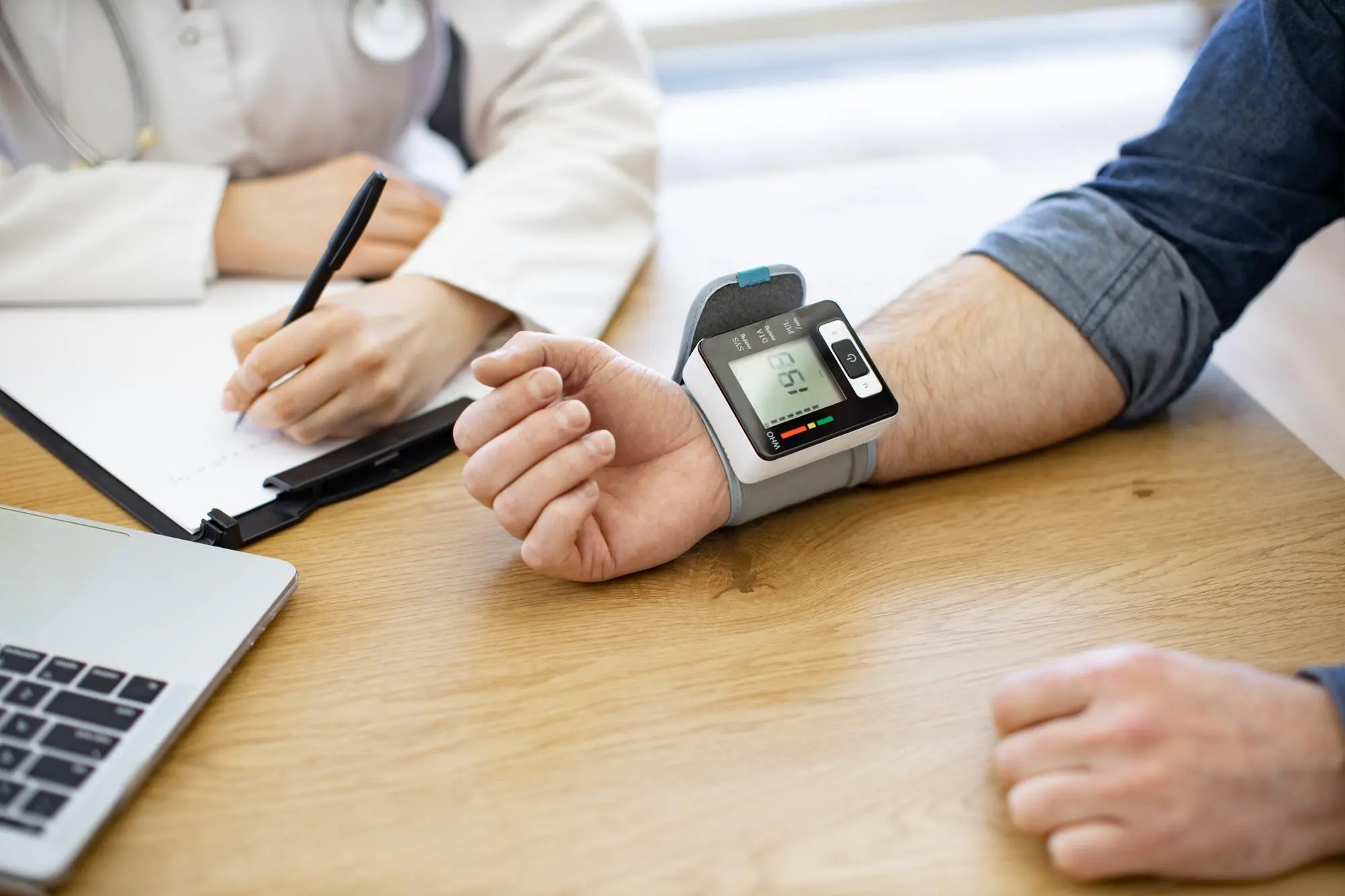 Doctor using a digital blood pressure monitor during a routine health screening.