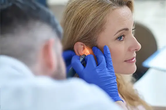 Doctor applying laser treatment to a woman’s ear for pain relief as ear pain treatments options.