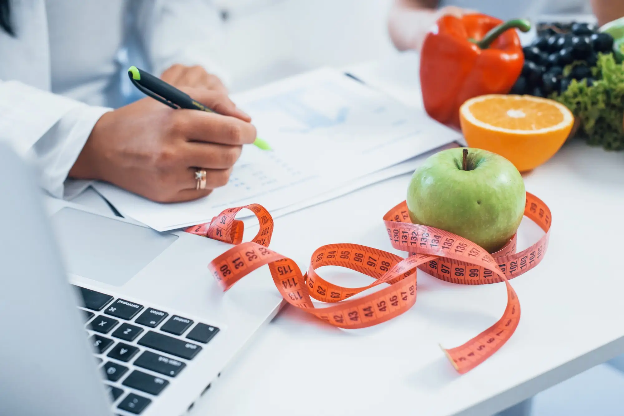 A variety of fresh fruits placed on a doctor's desk symbolizing nutritional support for weight loss.
