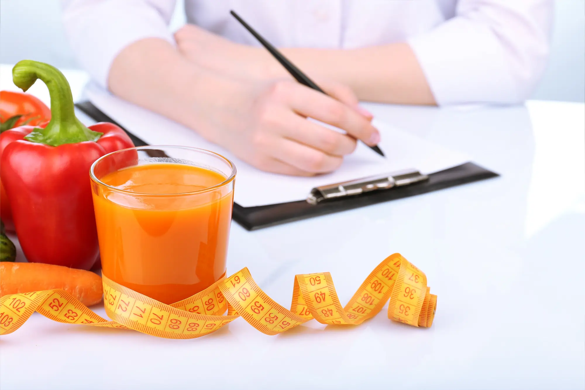 Fresh juices and vegetables placed on a doctor's table, representing a nutritional approach to weight loss management.