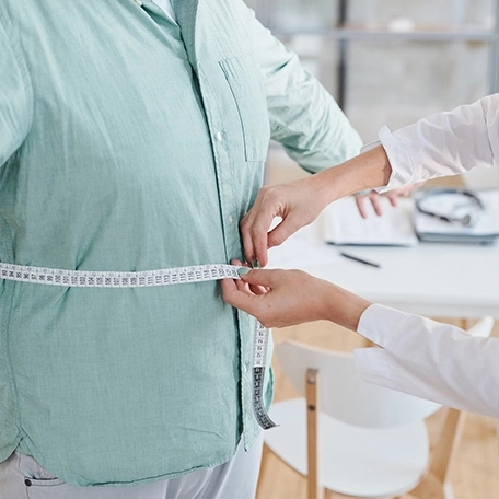 A female doctor measuring a patient's weight using a medical scale during a health checkup.