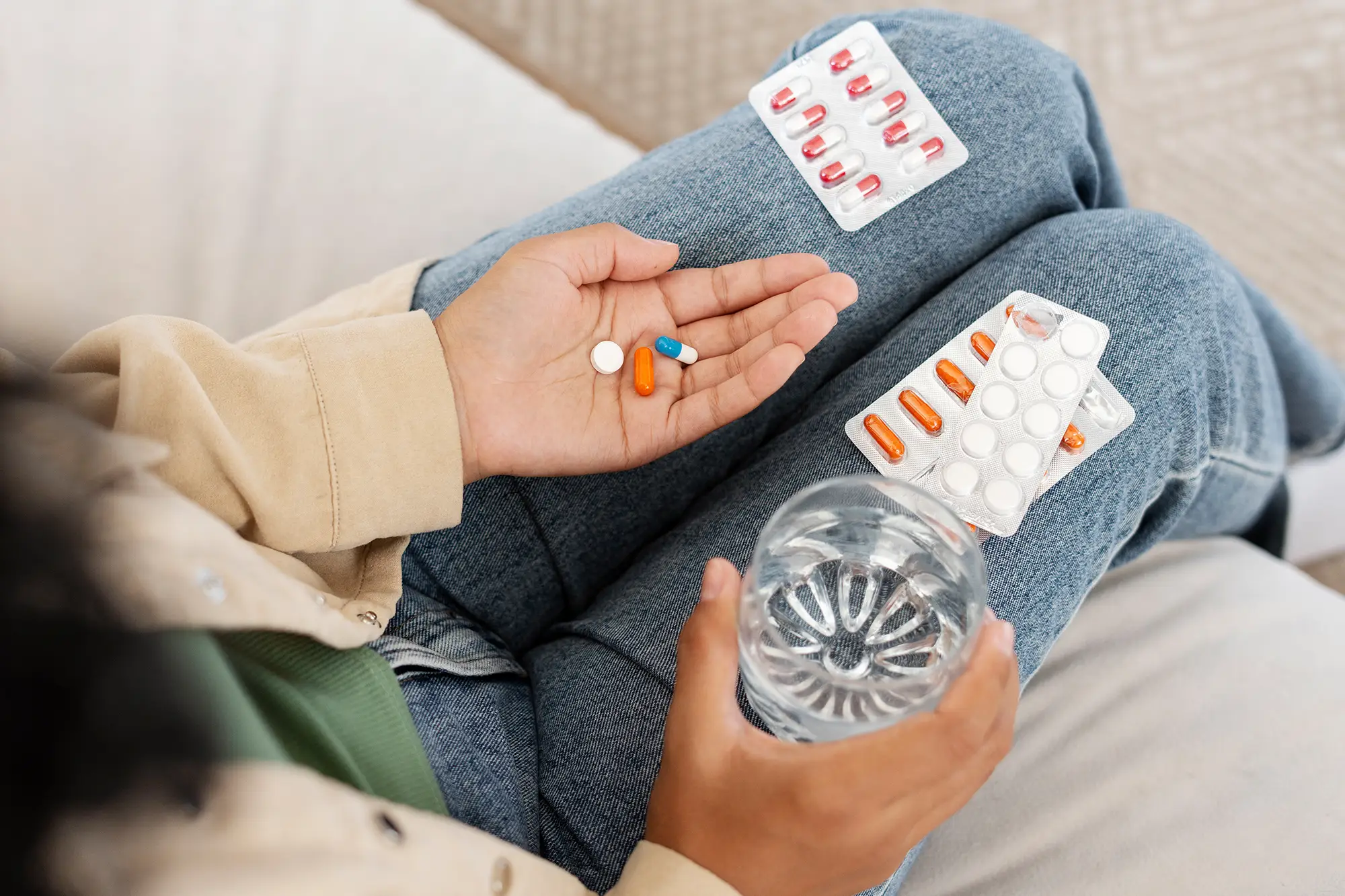 Woman taking prescribed medication with a glass of water, representing medication-assisted treatment.