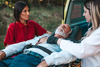 Unconscious man being transferred to an ambulance on a stretcher after experiencing trauma.