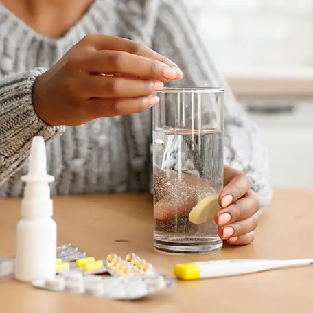Woman dissolving medication in a glass of water for oral intake.