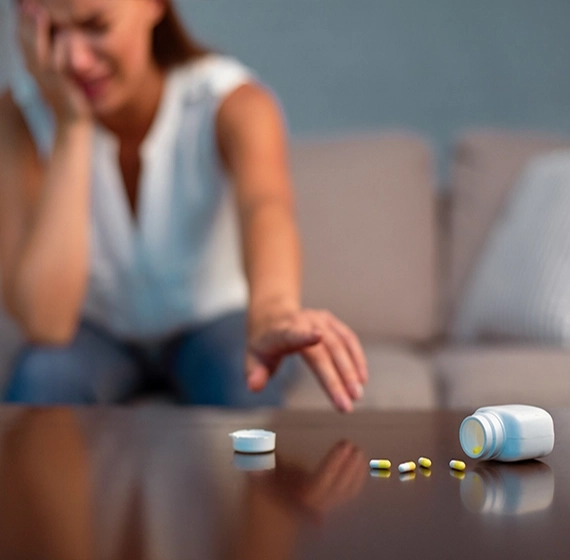 Distressed woman with tears in her eyes, reaching for medication, reflecting emotional struggle or health burden.