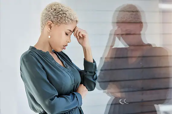 Woman holding her head and struggling with blurred vision, possibly experiencing trauma-related symptoms