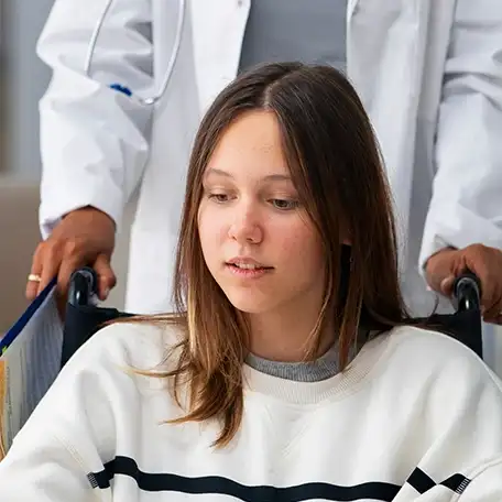 Woman sitting in a wheelchair with a distressed expression, symbolizing emotional or physical trauma.