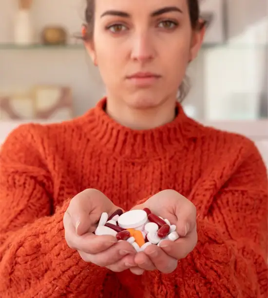 Woman with multiple medicine bottles in hand, suggesting ongoing health treatment.
