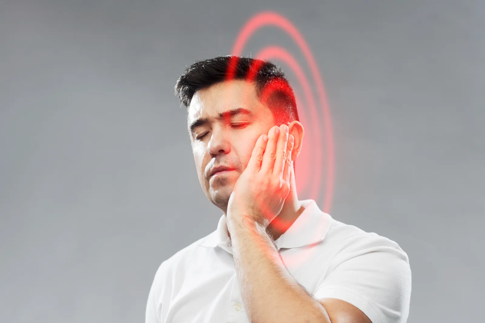 Man holding his jaw and ear area in discomfort, indicating ear or TMJ-related pain