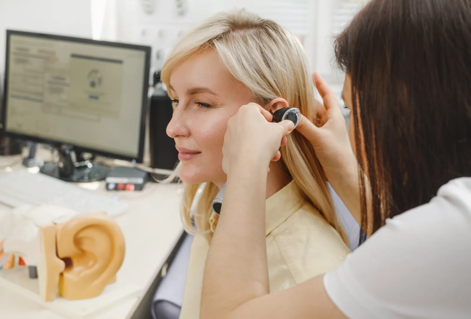 Otolaryngologist examining a patient's ear with an otoscope in a clinical office