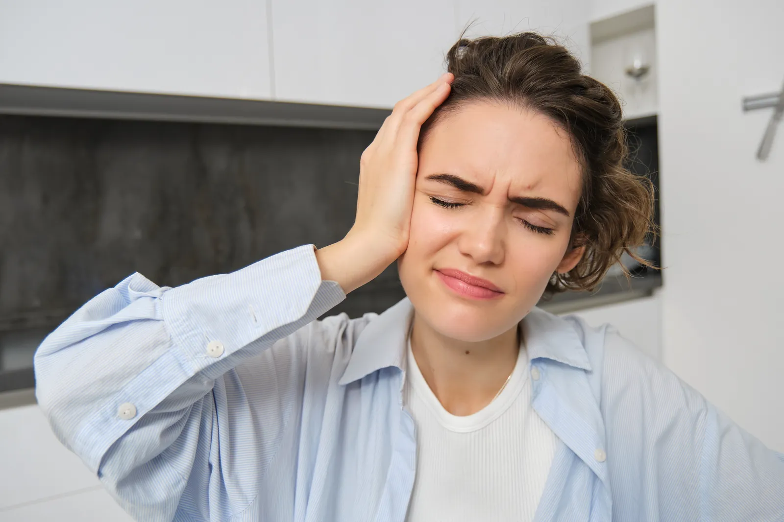 Woman holding her head experiencing ear pressure and dizziness