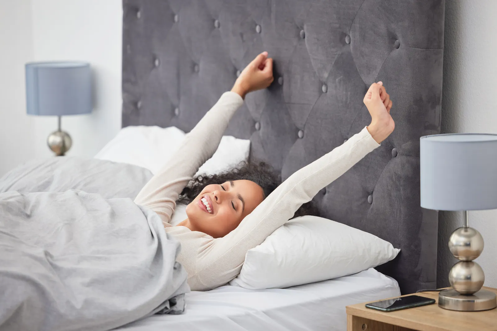 Woman stretching and smiling after waking up in bed
