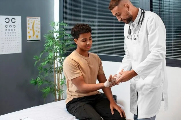 Doctor wrapping a teenage patient's wrist with a bandage in a pediatric exam room