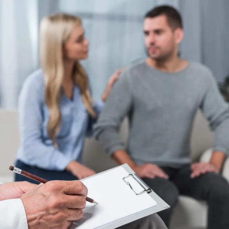 Female doctor handing a prescription bottle to a woman while a man sits beside her during a couples health consultation