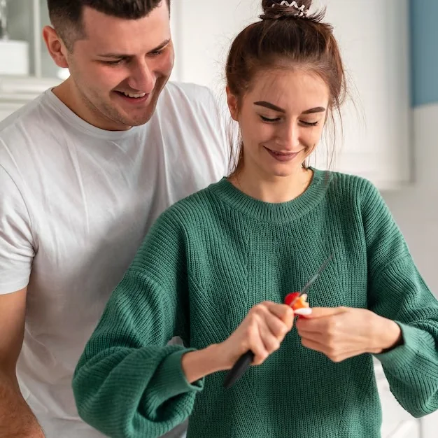 Smiling couple preparing food together in a bright kitchen, representing healthy relationships and sexual wellness