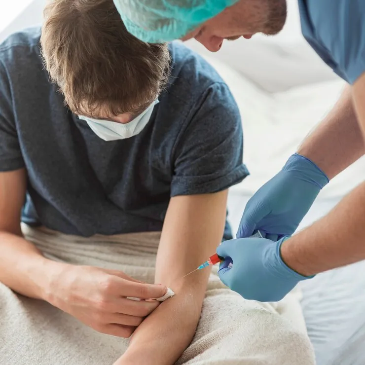 Doctor holding a medication vial while explaining injection therapy to a male patient
