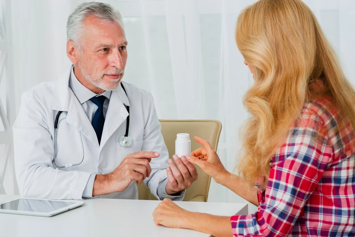 Senior male doctor explaining a medication bottle to a female patient during a hormone replacement therapy visit