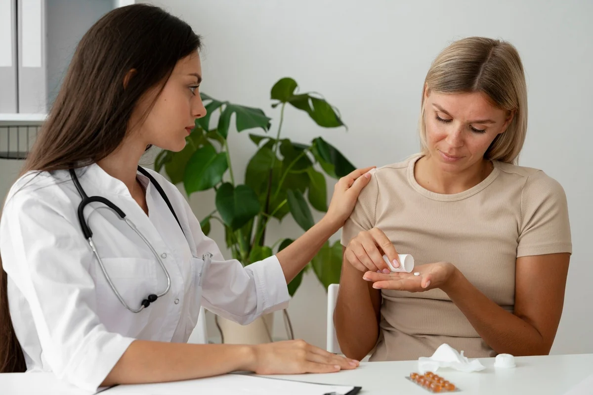 Female provider gently comforting a woman who holds a pill in her palm during a hormone therapy consultation