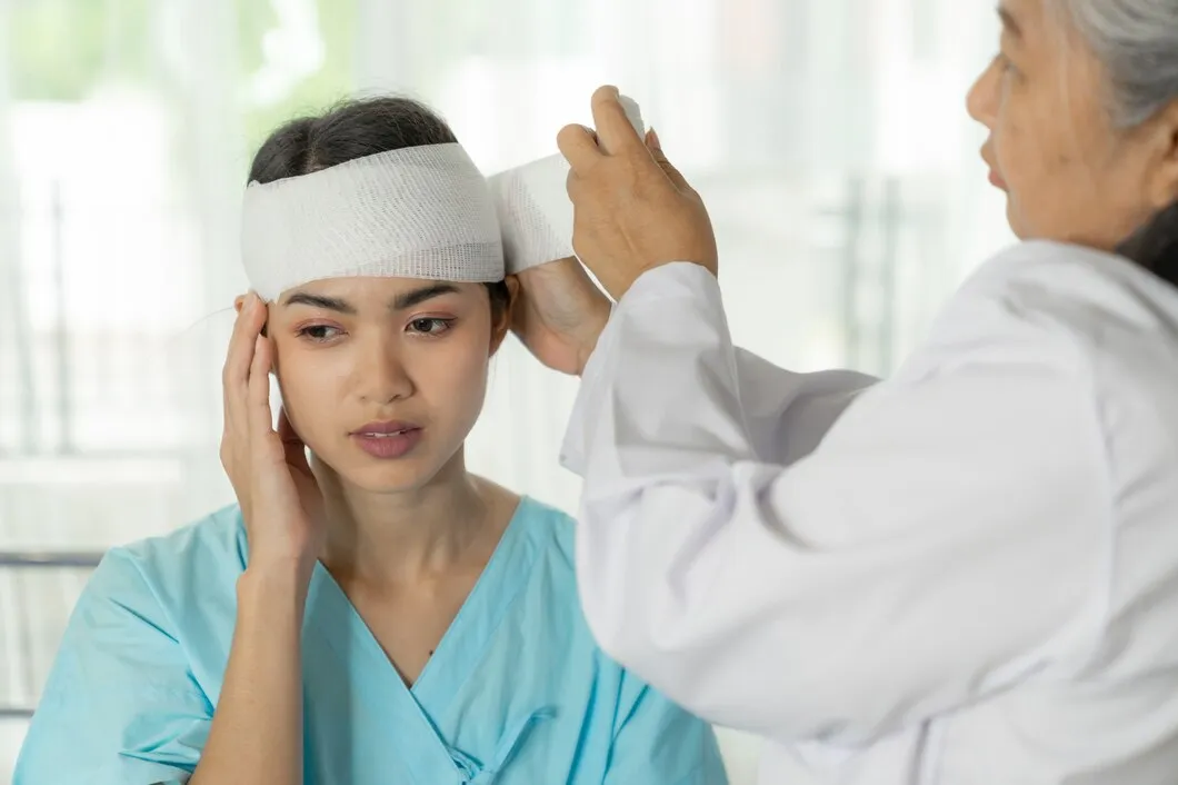 Female provider gently examining the head injury of an older woman during a medical exam